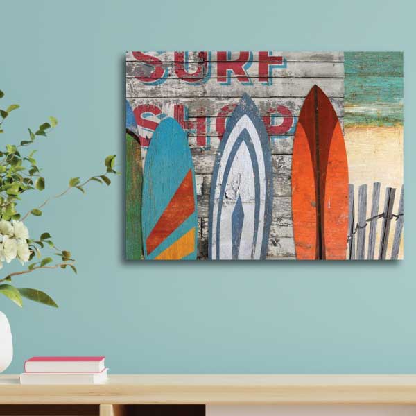 Wall art with image of colorful surfboards against the wall of a surf shop with beach in the background
