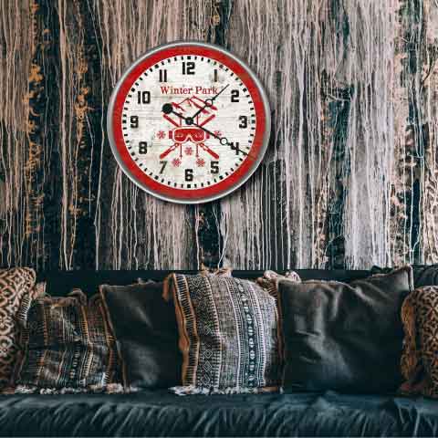 Round red clock with ski goggles and skis above couch