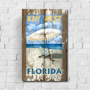 Key West Florida beach scene with umbrella and chair; brick wall