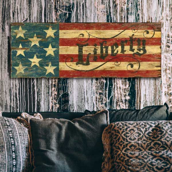Weathered wood with US flag and the word "Liberty" hung on a wood paneled wall