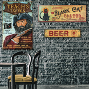 photo of a tavern wall with three wood signs as decorations; pirate, cat and BEER