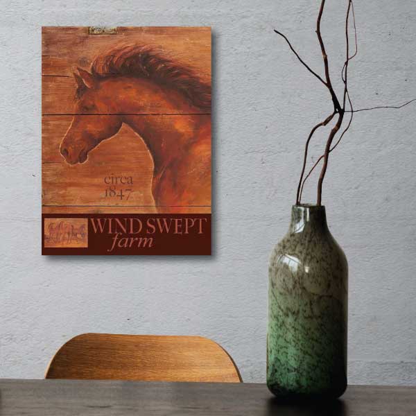 vintage-style wood sign of horse with text Wind Swept farm hung on a white wall behind desk